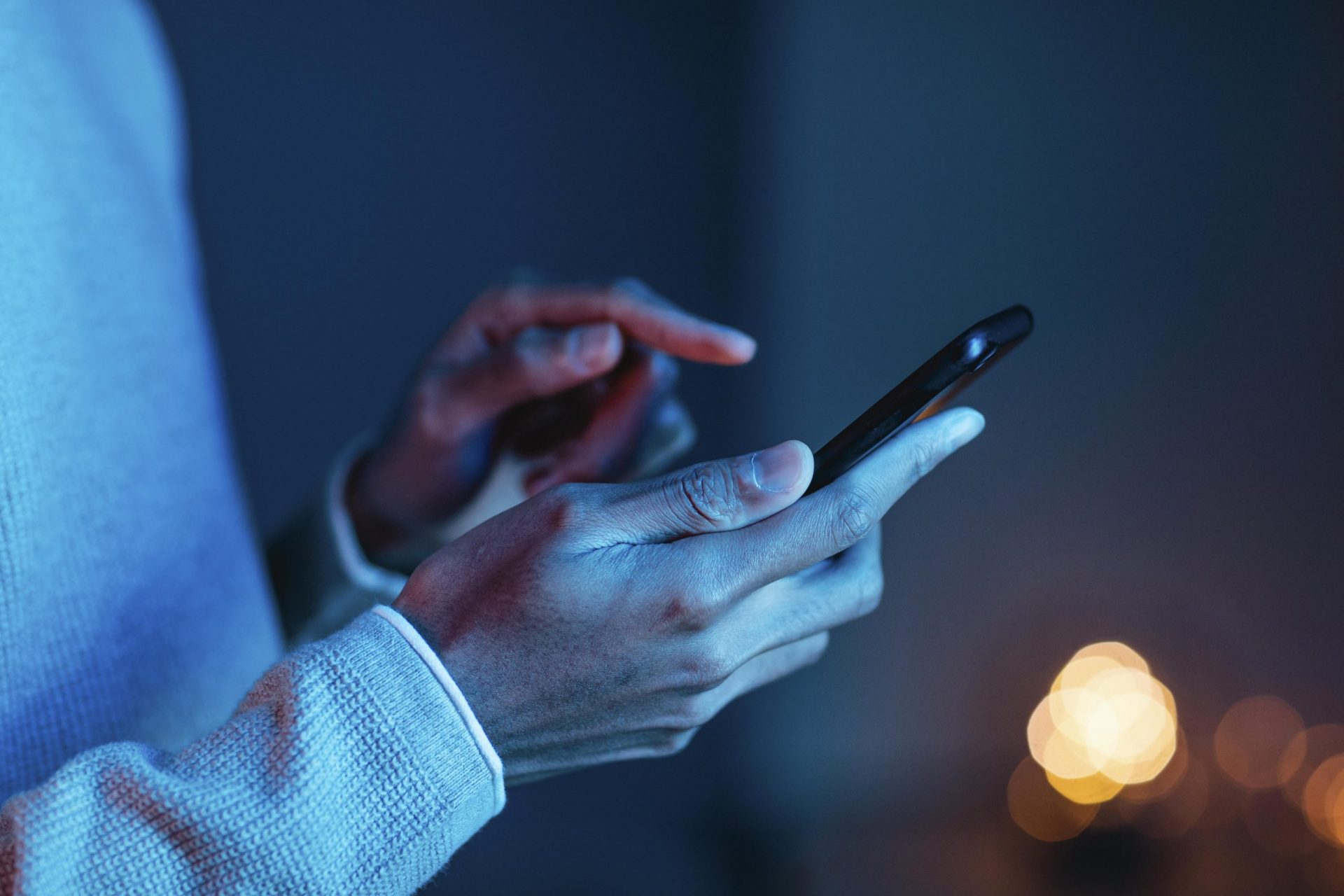 Mão de pessoa negra segurando um celular, olhando aplicativos